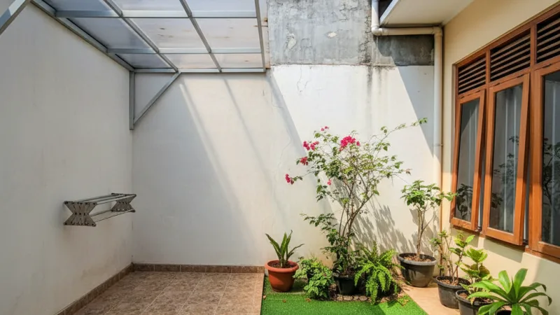 Taman belakang rumah tipe 36 dengan area jemur berkanopi transparan dan taman mini yang rapi.