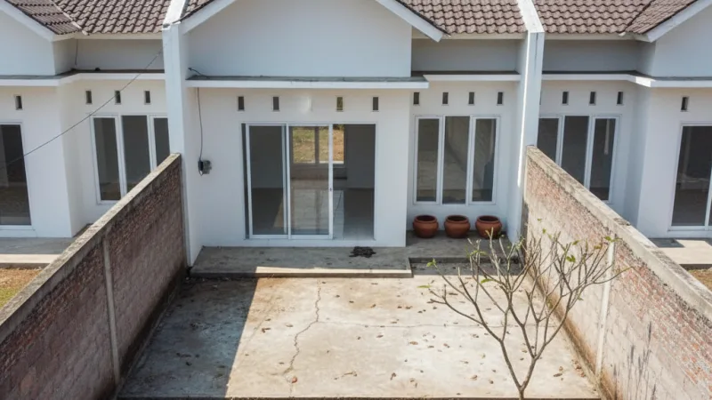 Area belakang rumah tipe 36 yang masih kosong dan belum tertata, siap untuk diubah menjadi taman.